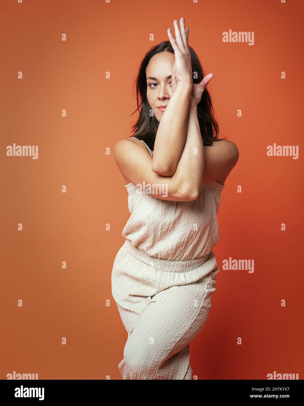 Smiling woman standing with legs crossed at ankle against background