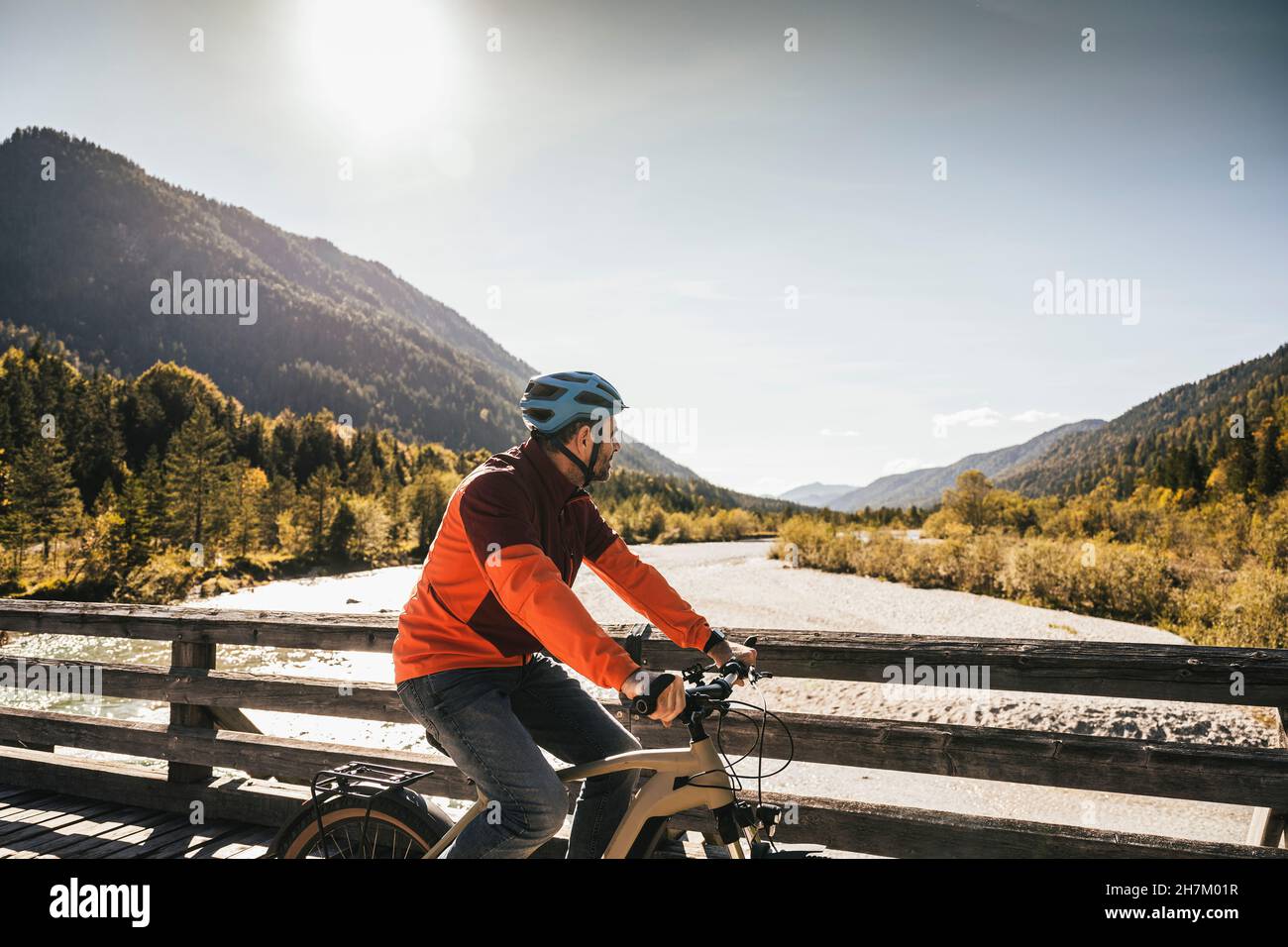 Man wearing helmet cycling on bridge Stock Photo