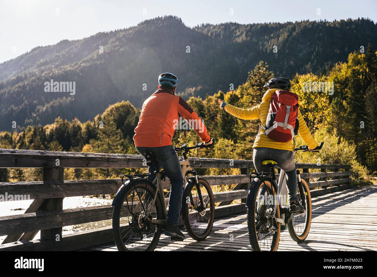 Woman pointing while cycling with man on bridge Stock Photo