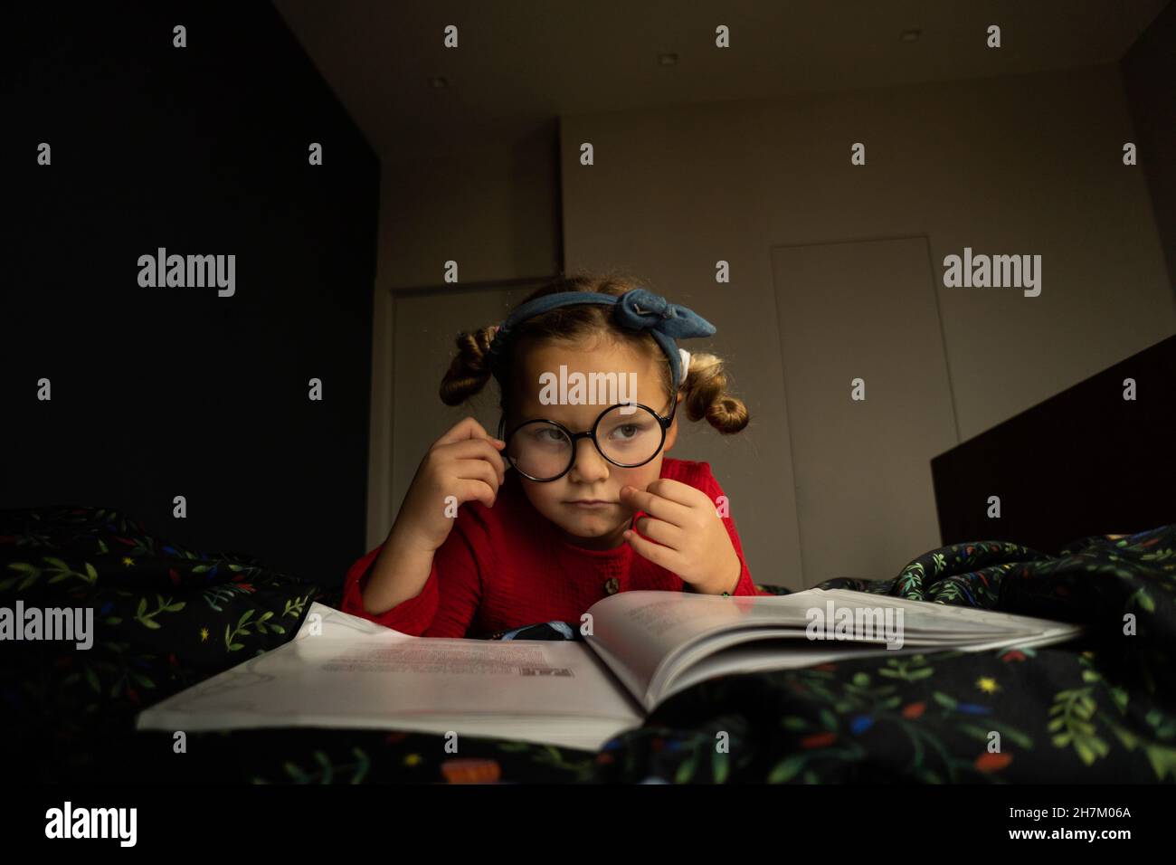 Thoughtful girl holding eyeglasses on bed Stock Photo