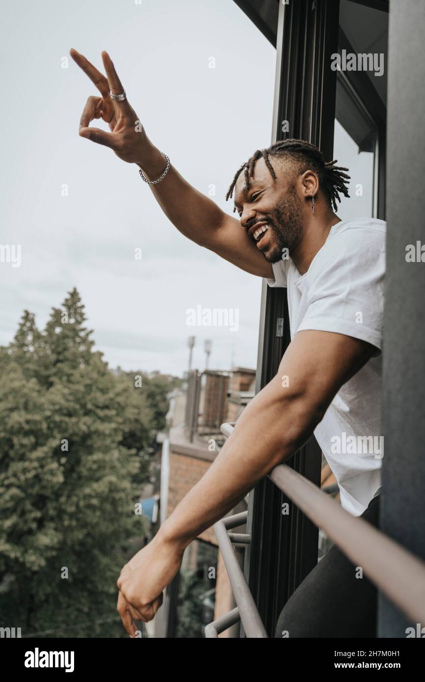 Man gesturing peace sign while leaning on railing Stock Photo