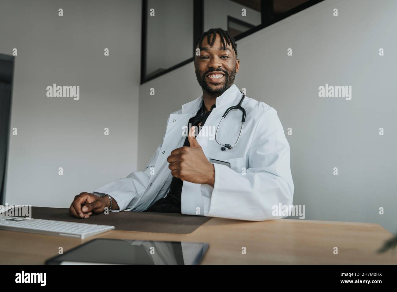 Young doctor gesturing thumbs up in office Stock Photo