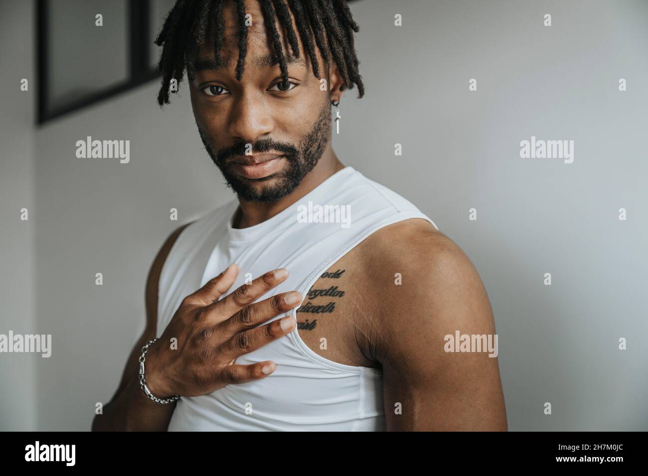Young man with hair locs showing tattoo Stock Photo - Alamy