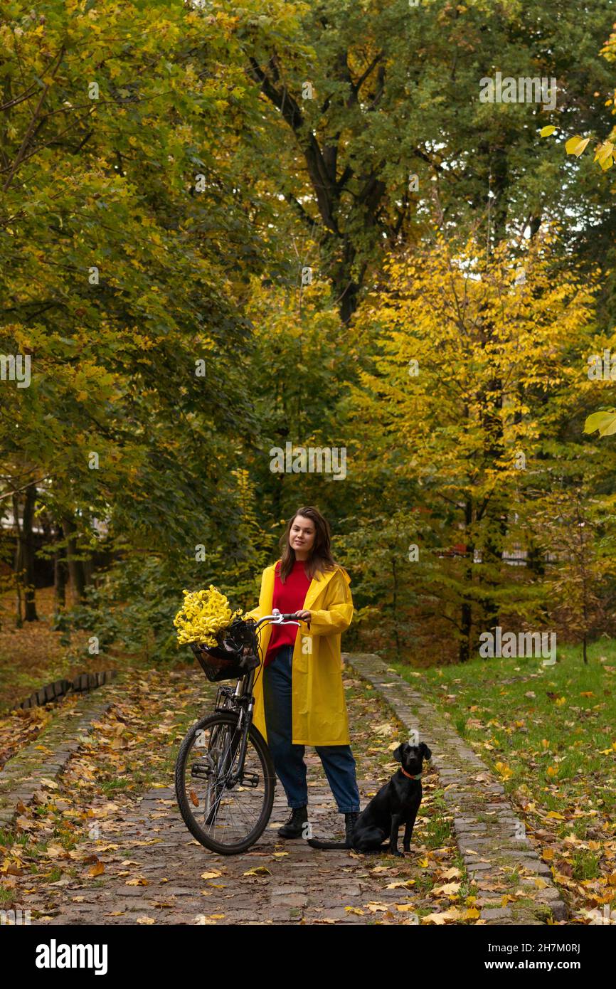 Woman standing with bicycle and dog at public park Stock Photo