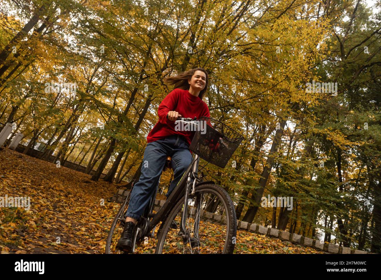 Smiling woman cycling in autumn park Stock Photo