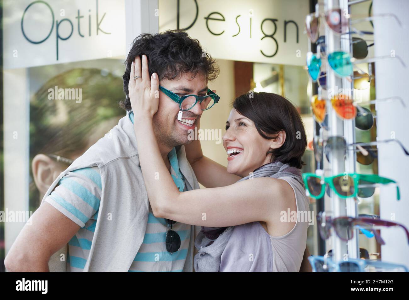 Happy woman trying eyeglasses on boyfriend at store Stock Photo
