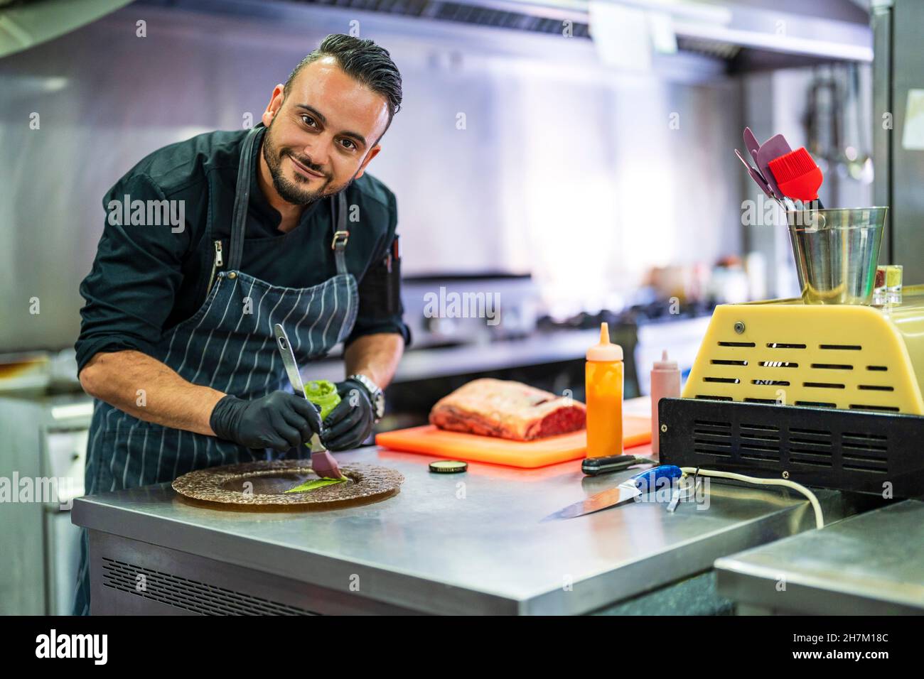 Smiling chef decorating plate for presentation in kitchen of restaurant Stock Photo