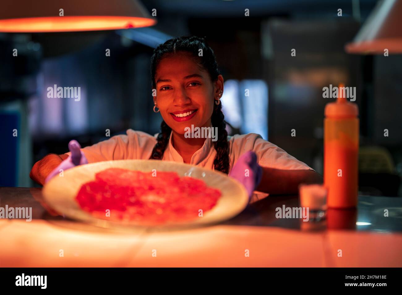 Smiling kitchen assistant showing carpaccio in plate Stock Photo