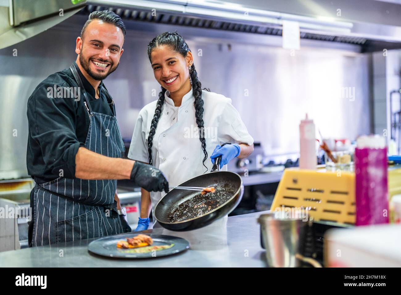 Smiling kitchen assistant helping chef in preparing food in restaurant Stock Photo Alamy