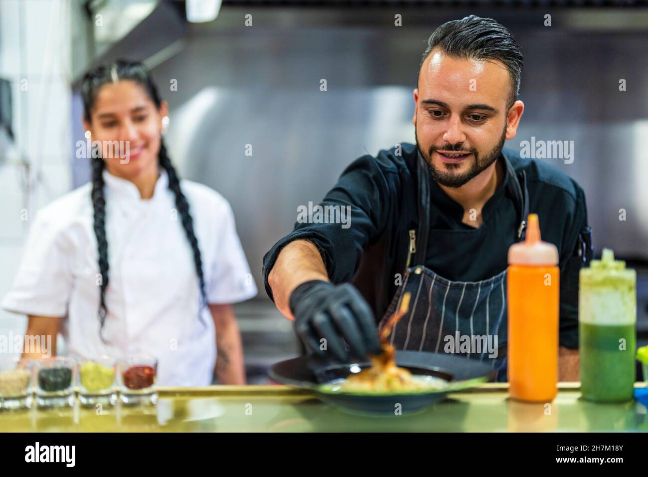 Chef decorating food with trainee in background Stock Photo