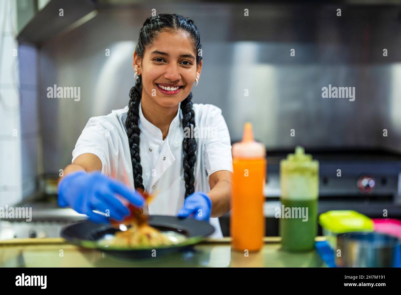 Smiling kitchen trainee food styling in restaurant Stock Photo