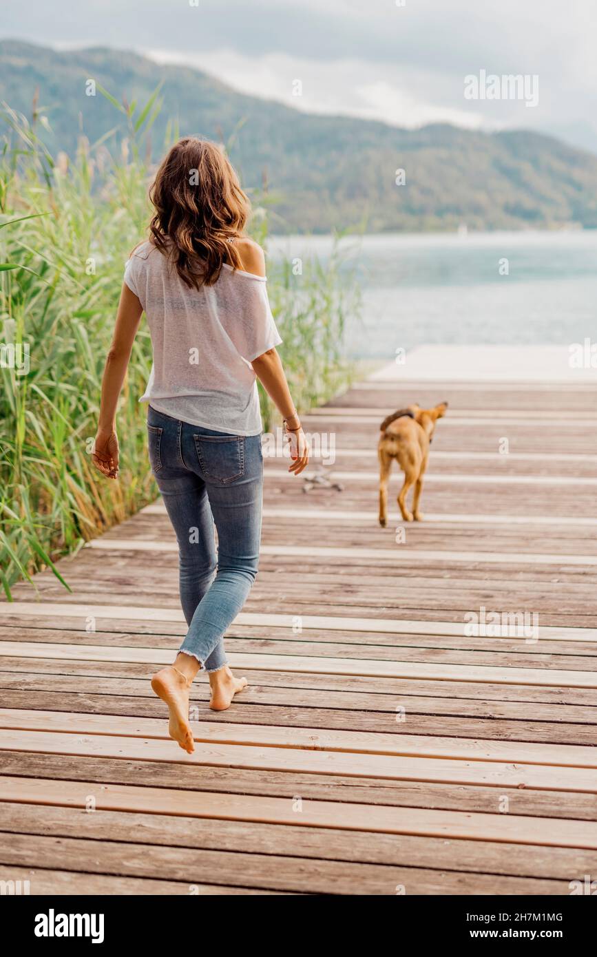 Woman and dog walking on jetty Stock Photo