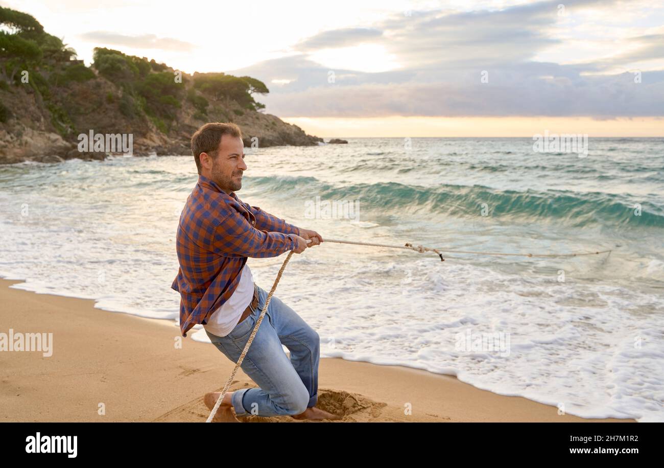 Man pulling rope from sea at beach Stock Photo Alamy