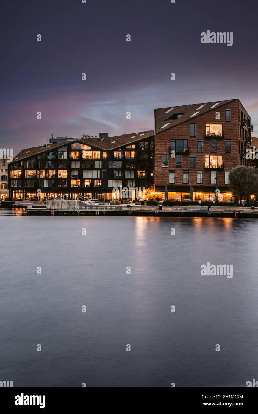 Illuminated buildings by canal at dusk, Copenhagen, Denmark Stock Photo