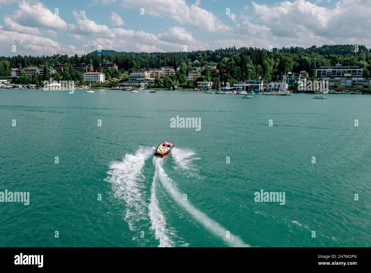 Austria, Carinthia, Velden am Worther See, Aerial view of motorboat leaving wake across turquoise waters of Worthersee lake Stock Photo