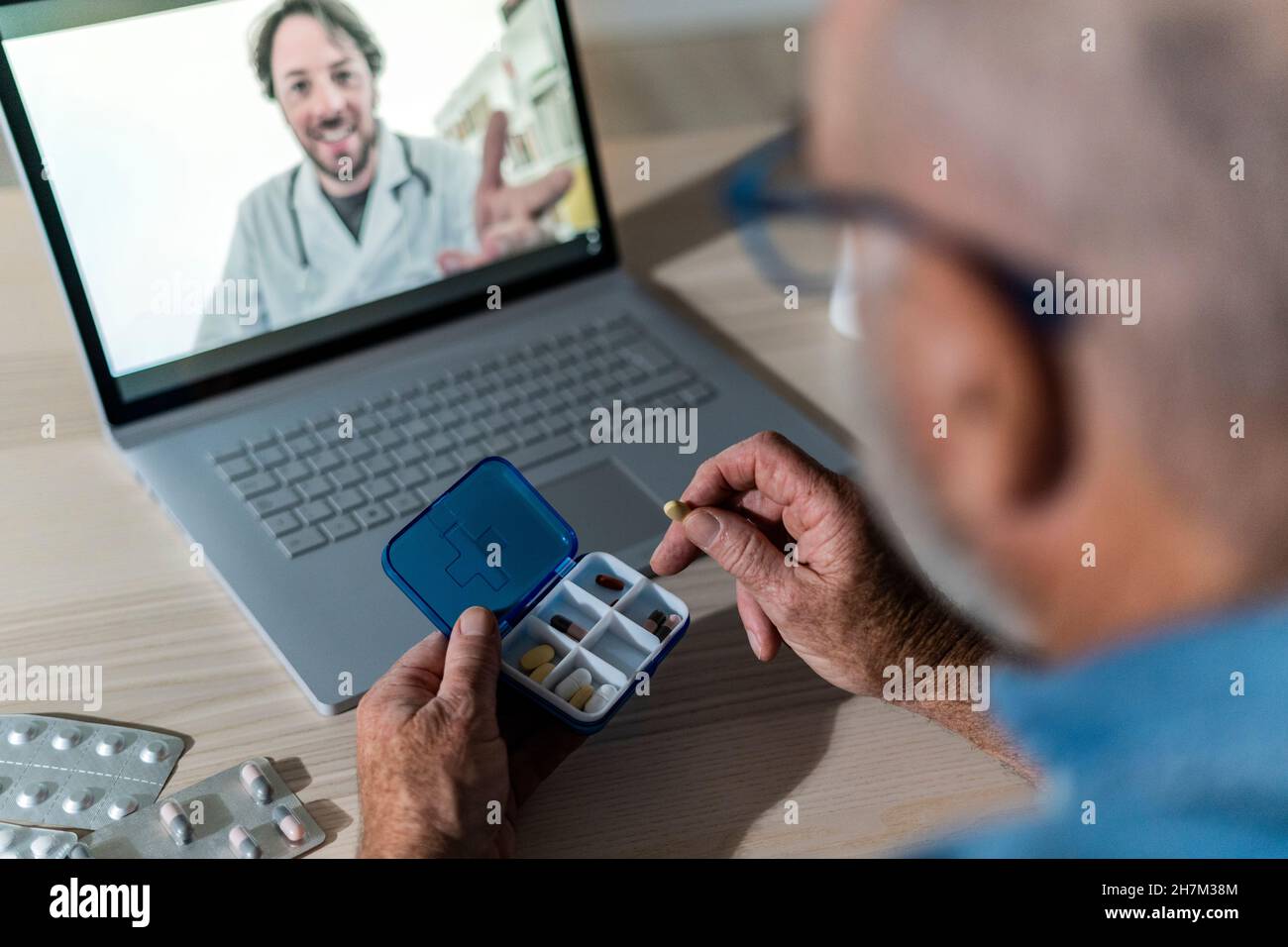 Hands of senior man taking out medicine from pill box at dining table Stock Photo
