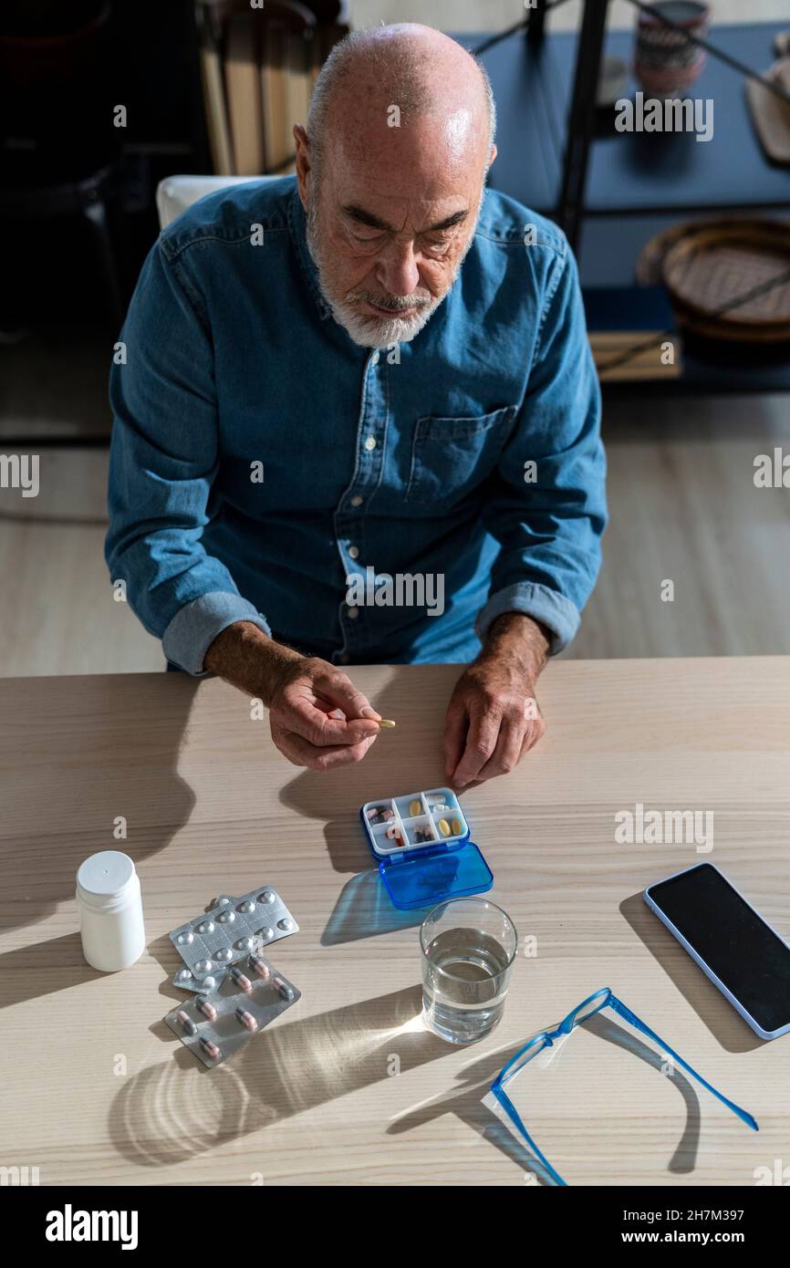 Man holding medicine by pill box at home Stock Photo