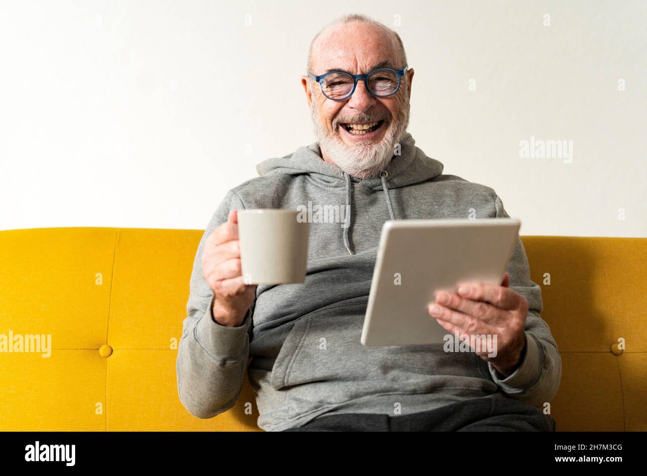 Bearded senior man doing online shopping through tablet PC at home Stock Photo