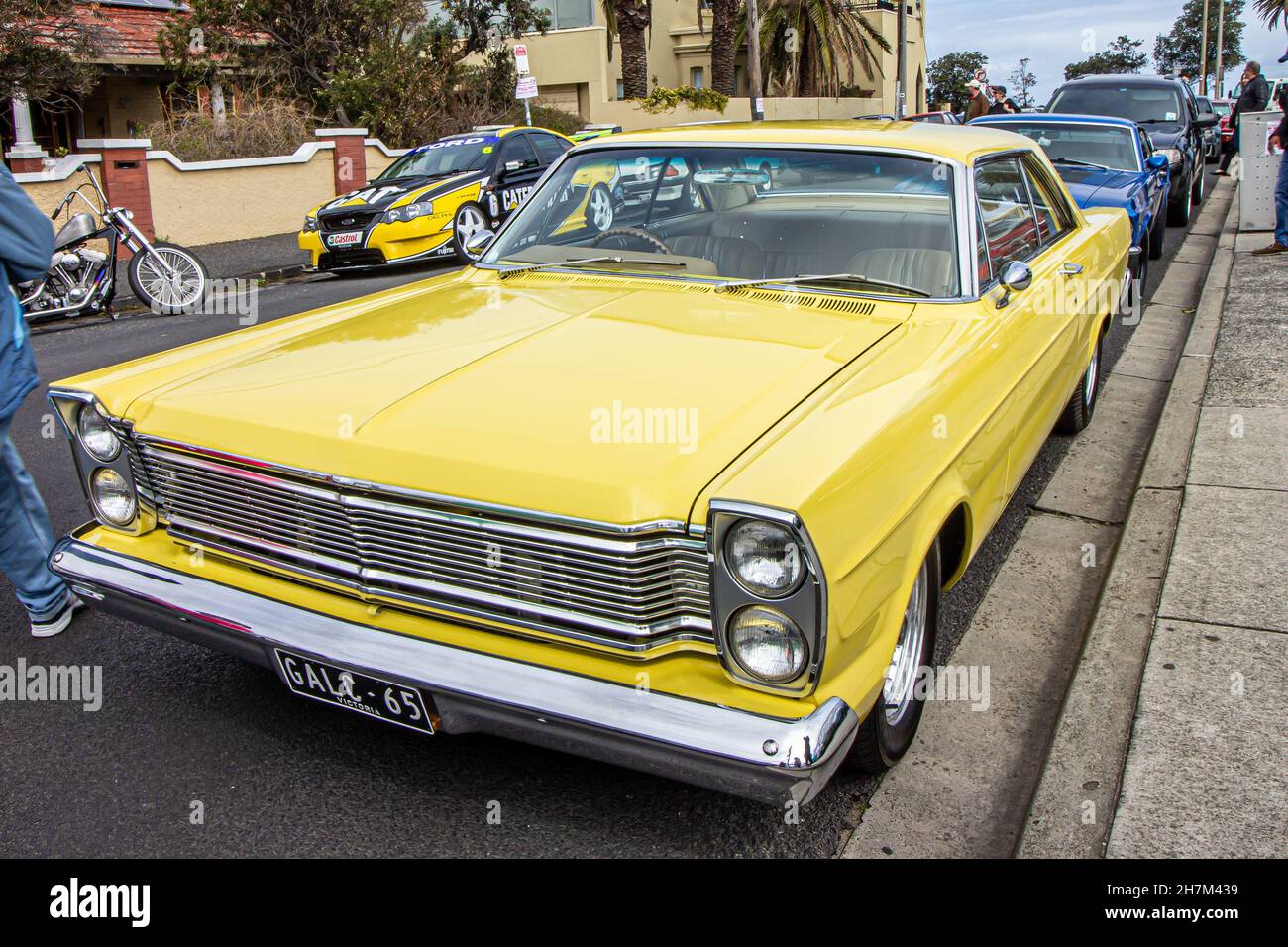 A classic yellow car parked in the streets of St Kilda, sunny day during the car show next to