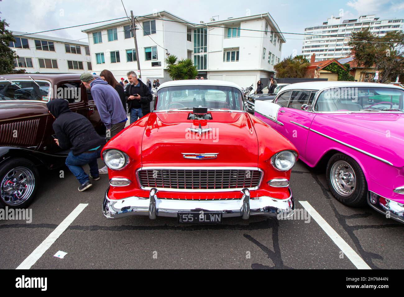 Red Chevrolet colourful classic car parked in a street, a white building in the back, some people around. St Kilda car show on fathers day. Melbourne, Stock Photo