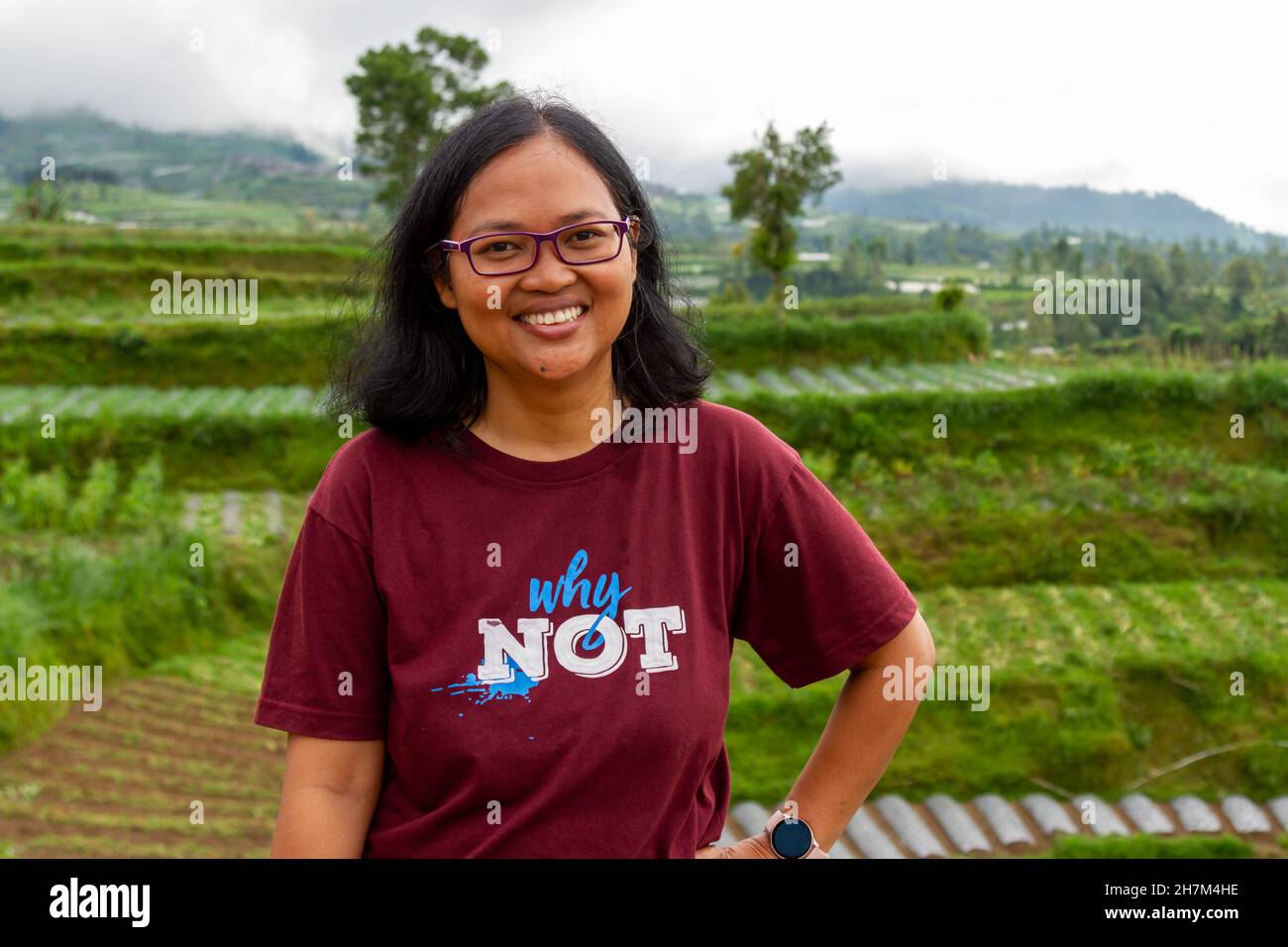 An asian woman smiling in the countryside with a background of vegetables planted on a terrace of a mountain, nature concept Stock Photo