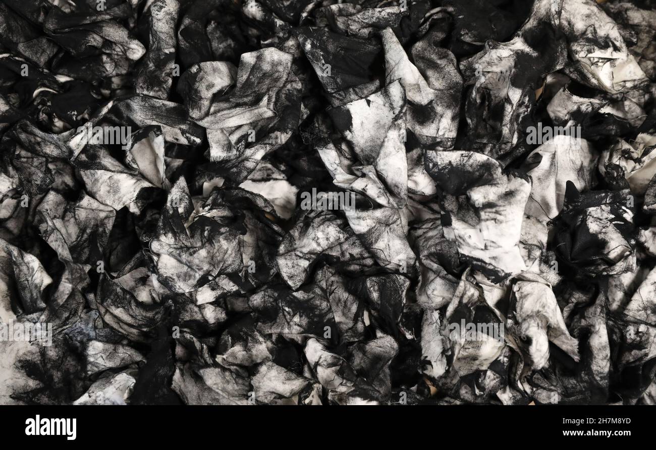 A mass of dirty used cloth wipes covered in black printers ink. Could also be oil dipstick wipes from mechanic. Unique abstract black and white backgr Stock Photo
