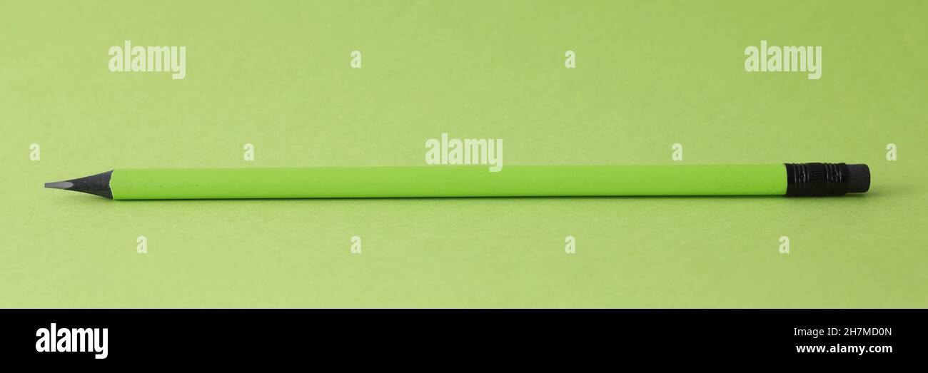 Sharp simple pencil lying on green background closeup Stock Photo
