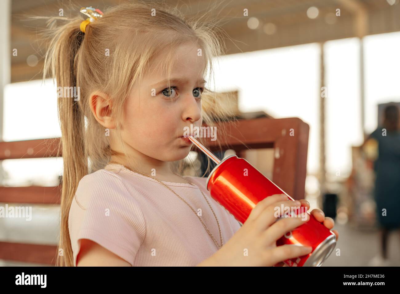 Little baby girl drinking soda with straw in outside cafe Stock Photo