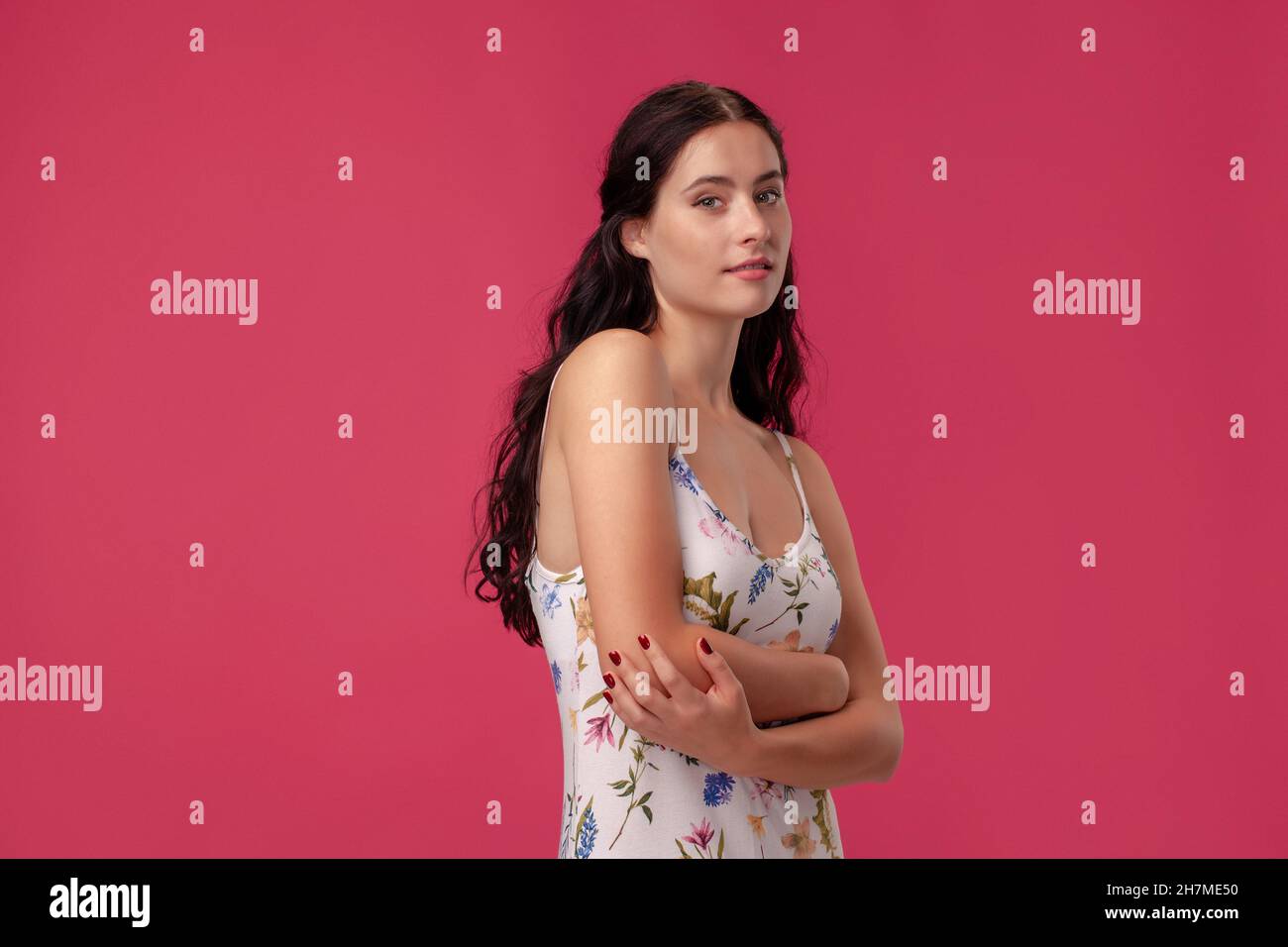 Portrait of a pretty young woman in a light dress standing on pink ...