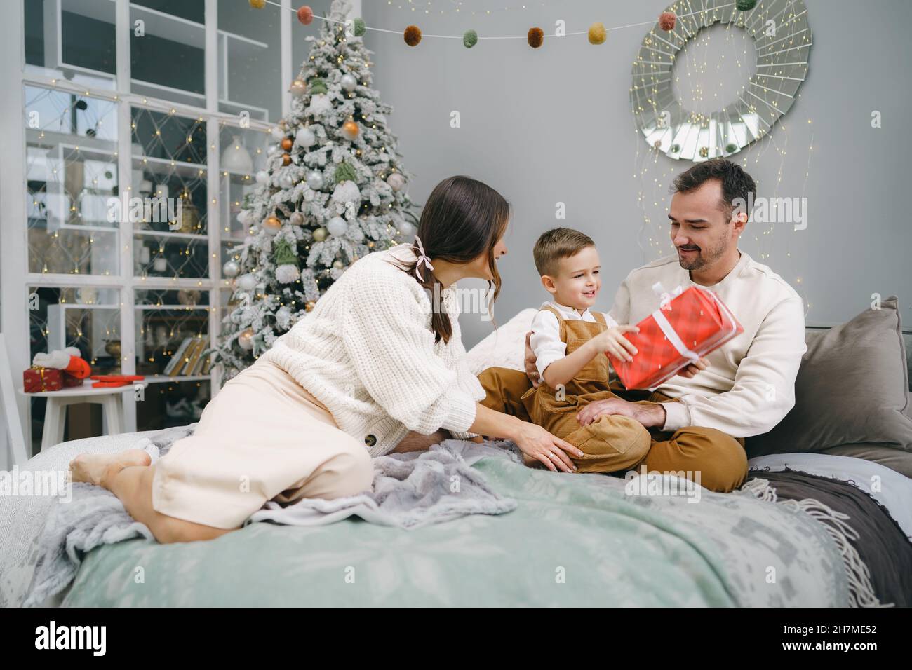 Smiling parents giving Christmas present to son at home Stock Photo