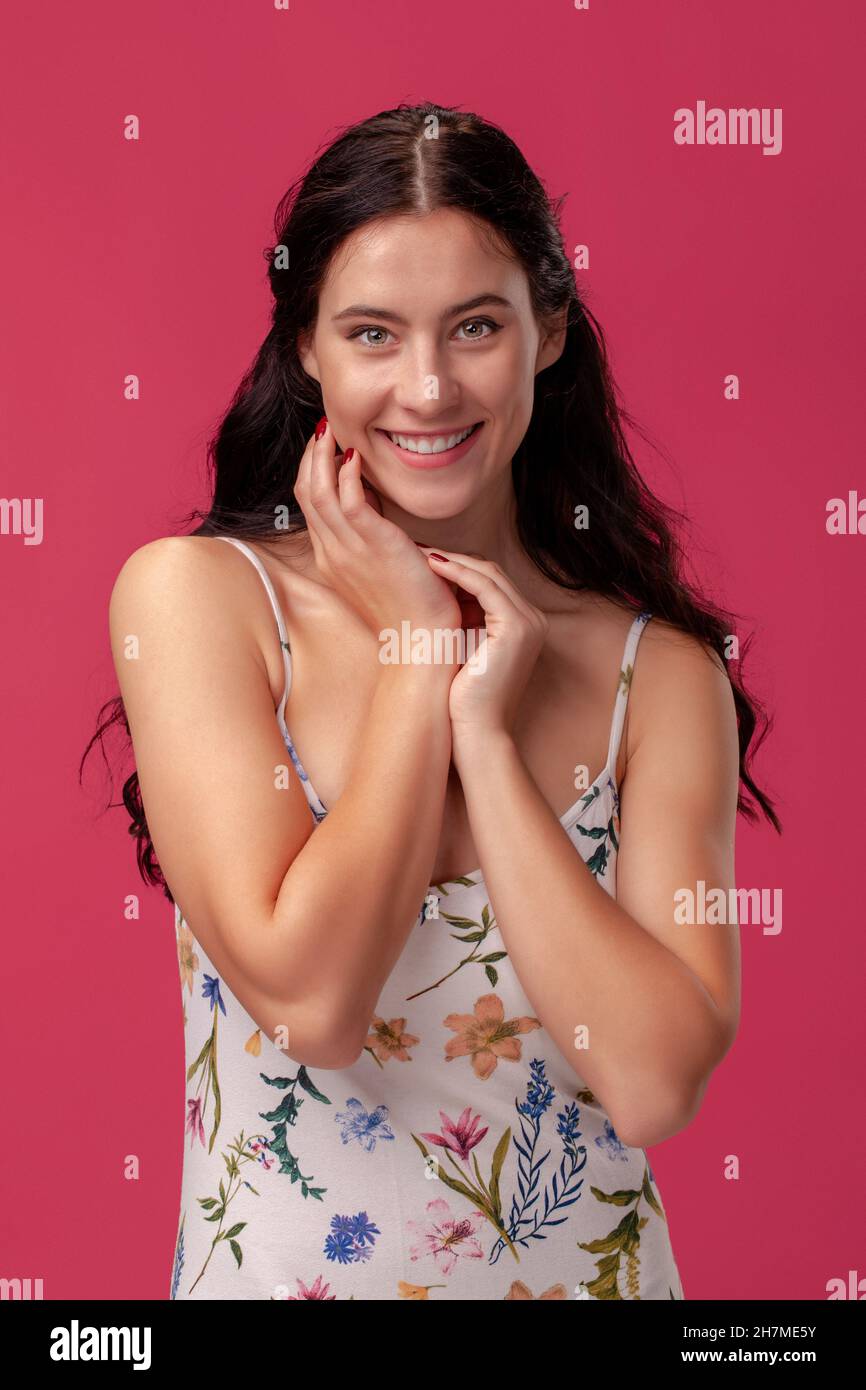Portrait of a pretty young woman in a light dress standing on pink ...