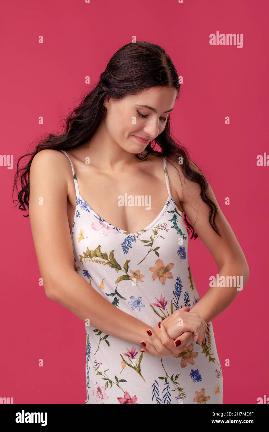 Portrait of a pretty young woman in a light dress standing on pink ...