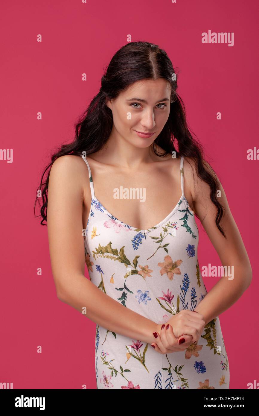 Portrait of a pretty young woman in a light dress standing on pink ...