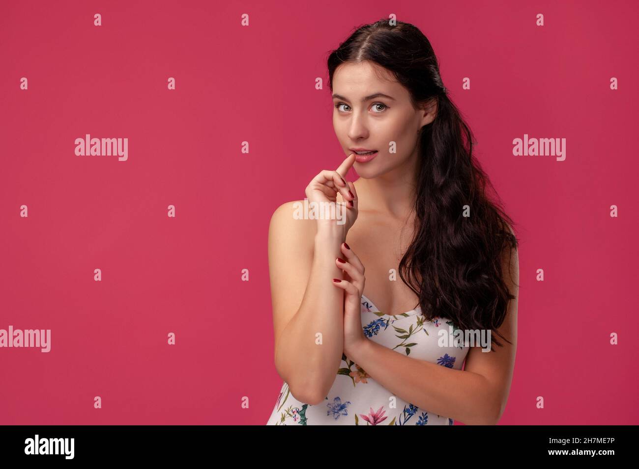 Portrait of a pretty young woman in a light dress standing on pink ...