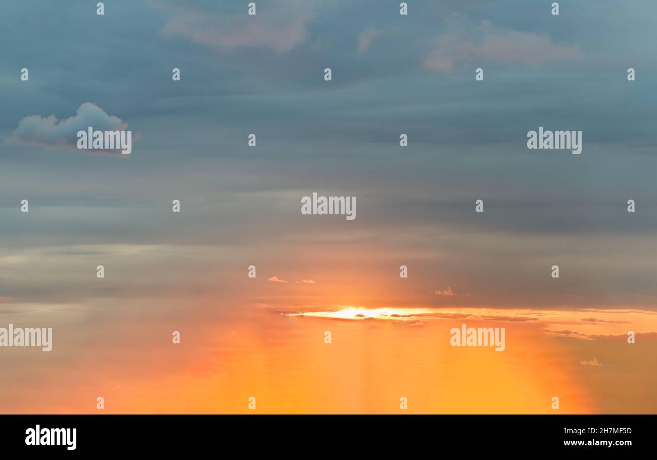 The sun shines through the clouds in the sunset sky with dramatic light ...