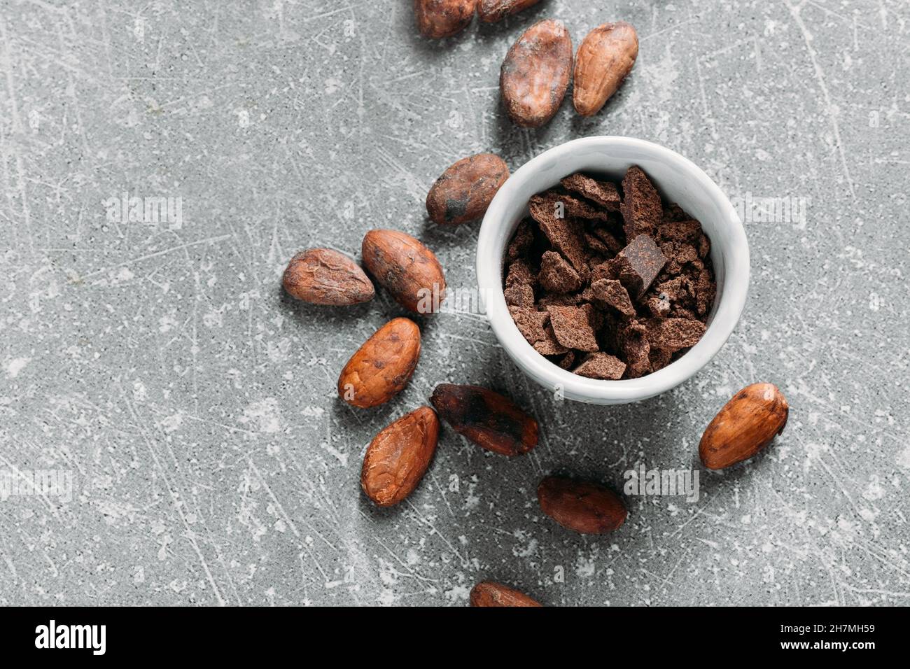 Cacao beans on grey concrete background. Raw fermented. organic cocoa seeds for hot chocolate drink. Flat lay, copy space for food and drink recipe Stock Photo