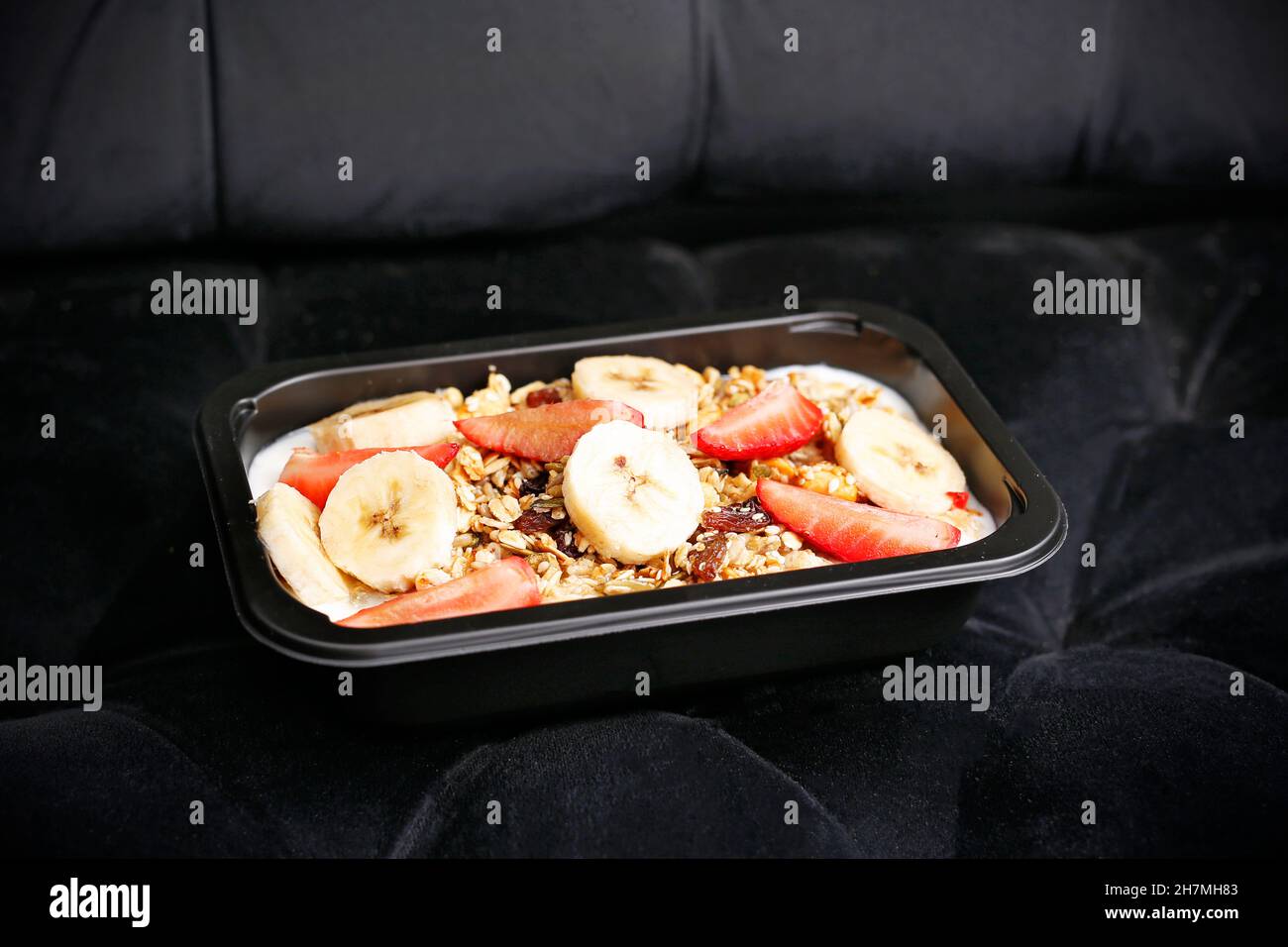 Porridge with fruits and nuts. A healthy nutritious breakfast in a box. Appetizing ready-to-go dish served in a disposable box. Culinary photography. Stock Photo