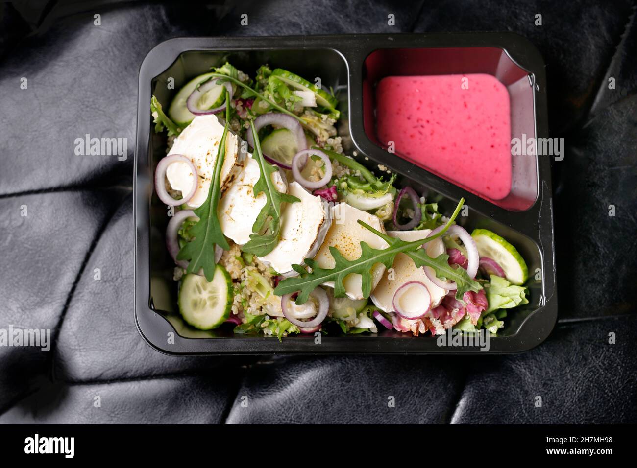 Takeaway, green salad with camembert cheese Appetizing ready-to-go dish served in a disposable box. Culinary photography. Food background. Stock Photo