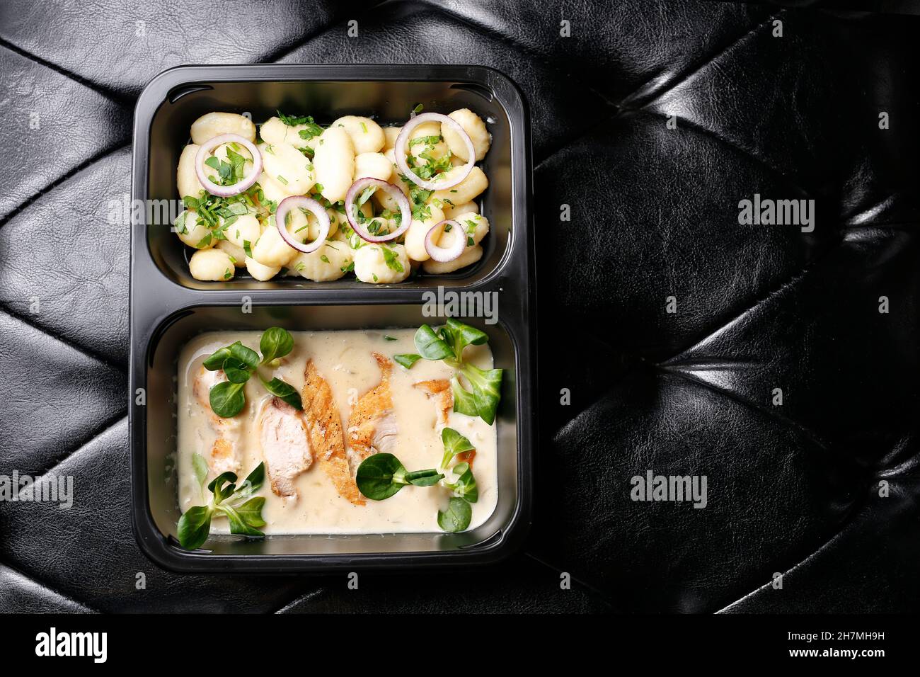 Gnocchi with chicken fillet boiled in cheese sauce. Dinner lunch box. Takeaway, diet box. Appetizing ready-to-go dish served in a disposable box. Cul Stock Photo
