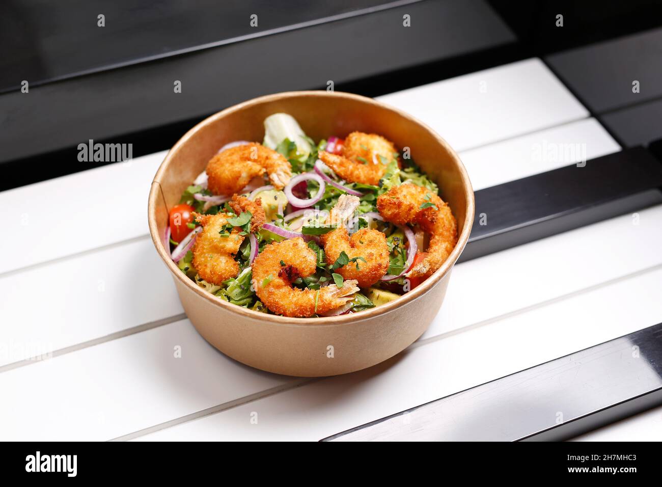Fried prawns on a green salad. Takeaway, diet box. Appetizing ready-to-go dish served in a disposable box. Culinary photography. Food background. Stock Photo