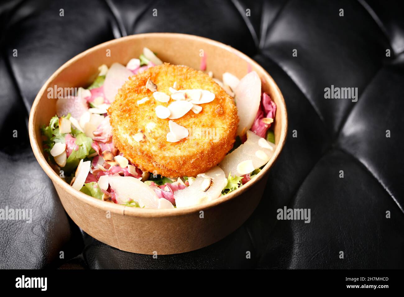 Fried camembert cheese on a green salad. Takeaway, diet box. Appetizing ready-to-go dish served in a disposable box. Culinary photography. Food backgr Stock Photo