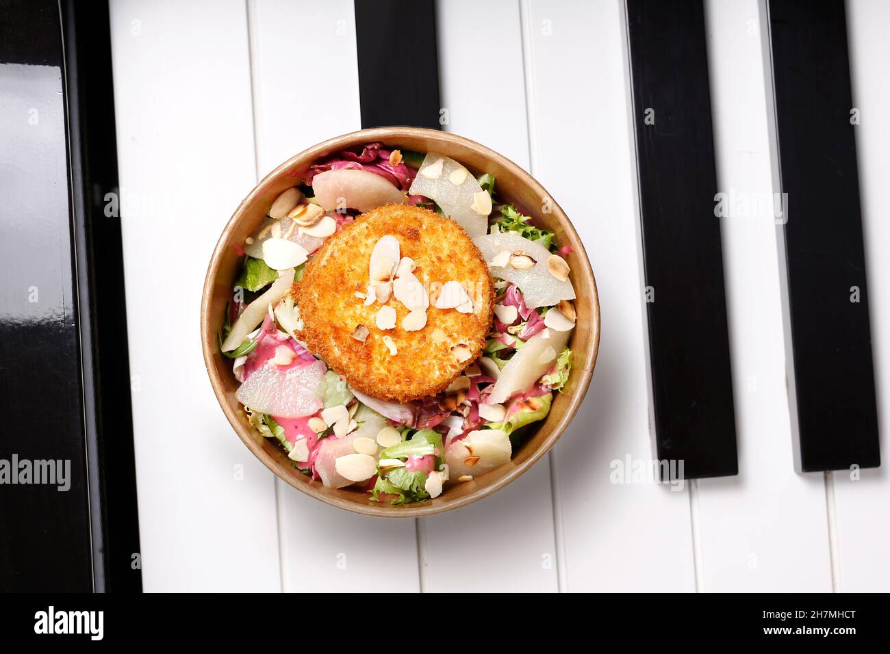 Fried camembert cheese on a green salad. Takeaway, diet box. Appetizing ready-to-go dish served in a disposable box. Culinary photography. Food backgr Stock Photo