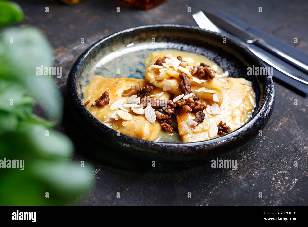 Pancakes with cheese in orange sauce served with caramelized nuts and almonds. Appetizing dish. Culinary photography, a proposal to serve a meal. Stock Photo