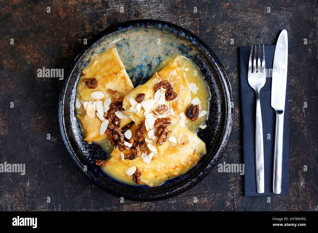 Pancakes with cheese in orange sauce served with caramelized nuts and almonds. Appetizing dish. Culinary photography, a proposal to serve a meal. Stock Photo