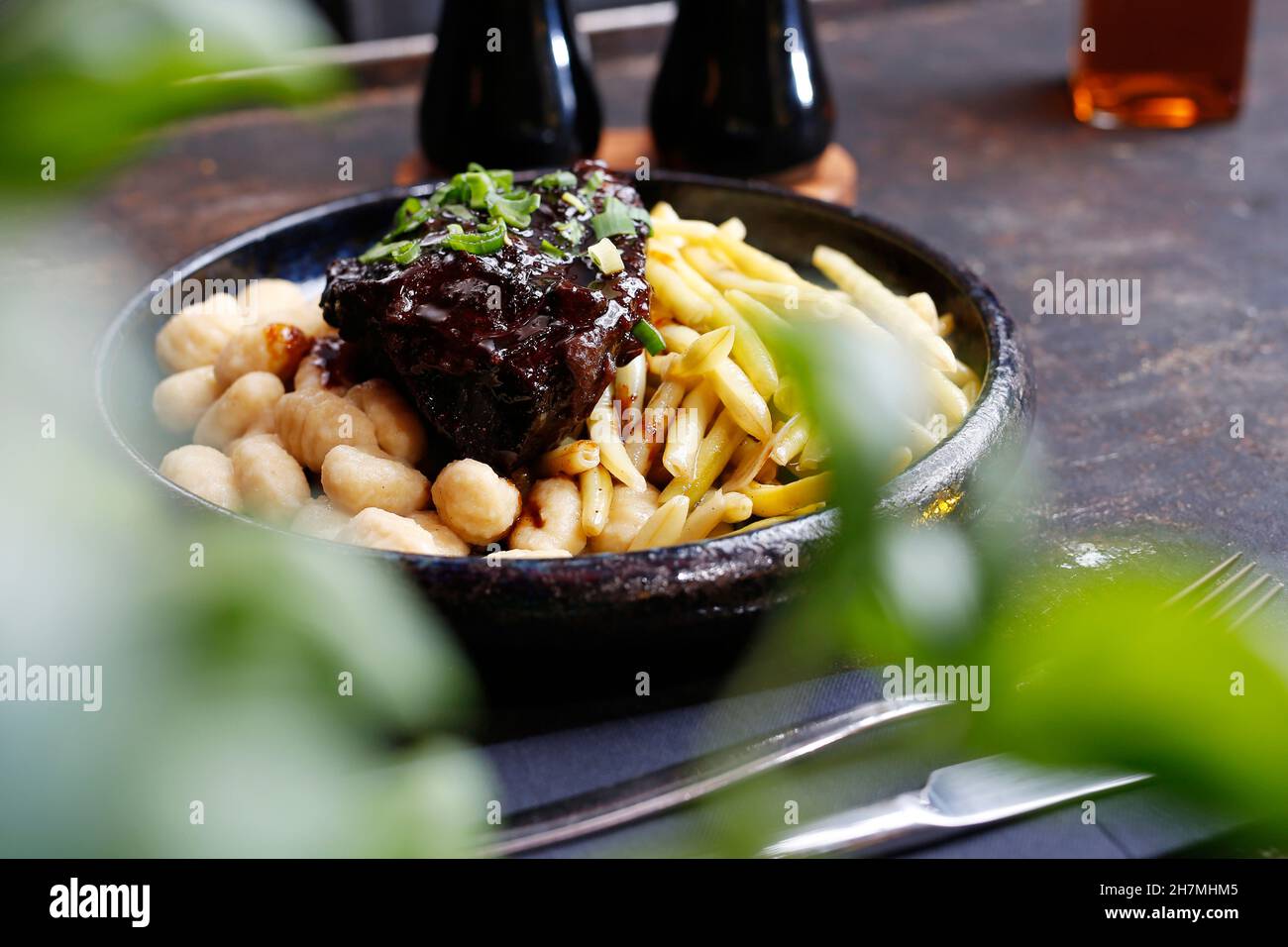 Roasted meat in bbq sauce with fries, and gnocchi. A tasty dish.Culinary photography. Suggestion to serve the dish. Stock Photo