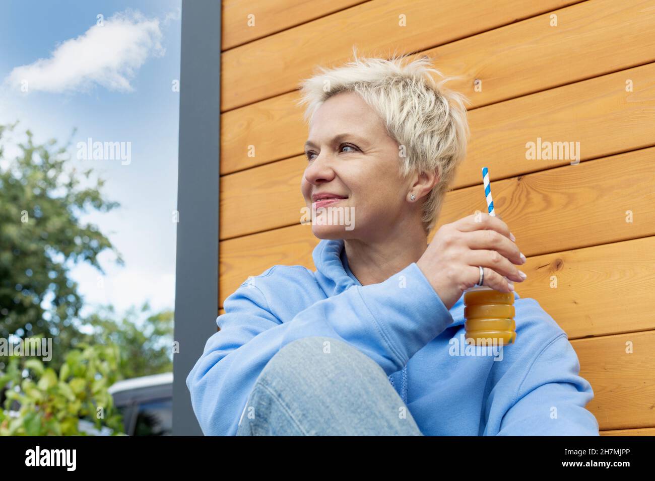 Happy woman enjoying juice with straw on patio Stock Photo