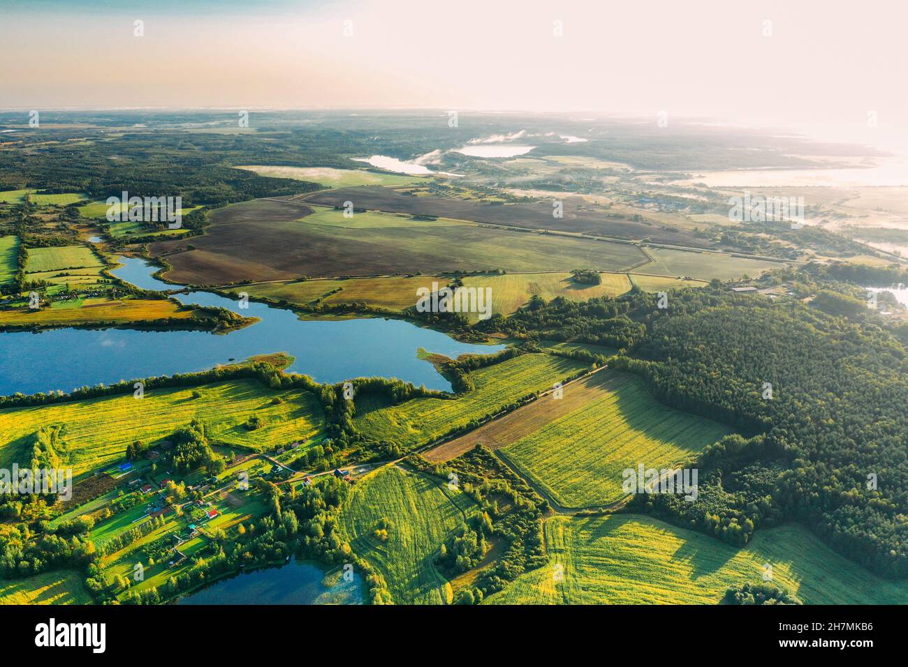Lyepyel District, Vitebsk Region, Belarus. Aerial View Of Residential Area With Houses In Countryside. Morning Fog Above Lepel Lake. Sun Shining Above Stock Photo
