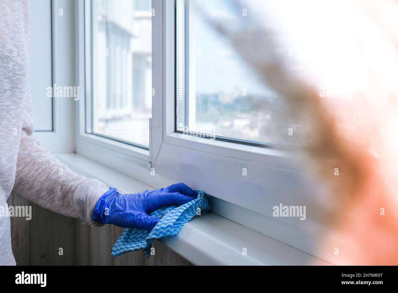 Cleaning the windowsill wiping dust by blue microfiber cloth for