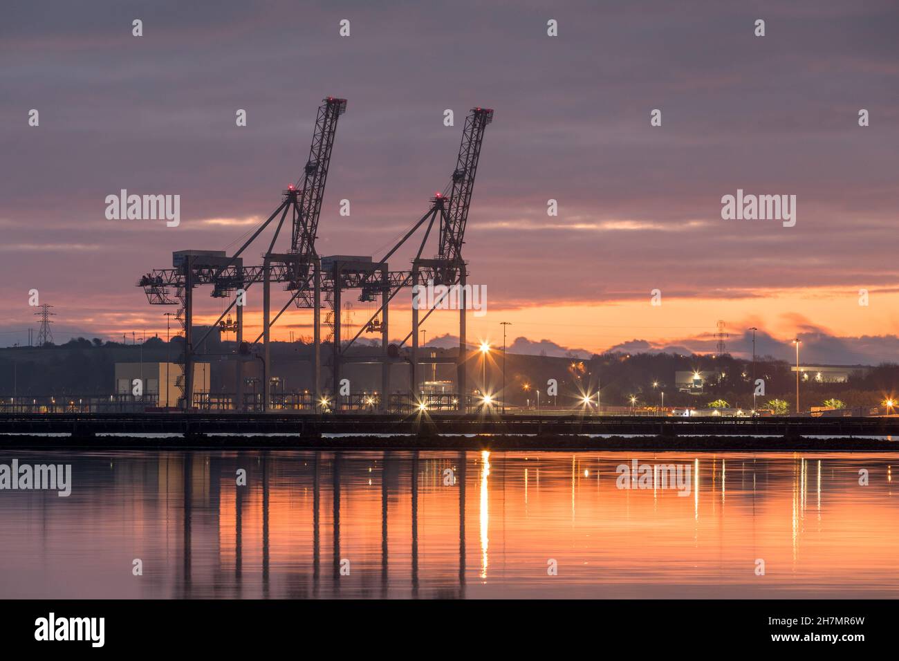 Ringaskiddy, Cork, Ireland. 24th November, 2021. Gantry cranes silhouetted by dawn light at the new Port of Cork container terminal at Ringaskiddy, Co. Cork, Ireland. - Credit; David Creedon / Alamy Live News Stock Photo