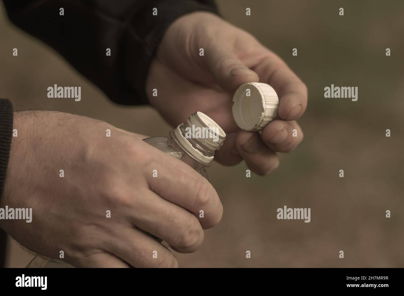 Two hands of a grown man holding a plastic bottle. Liquid fire starter